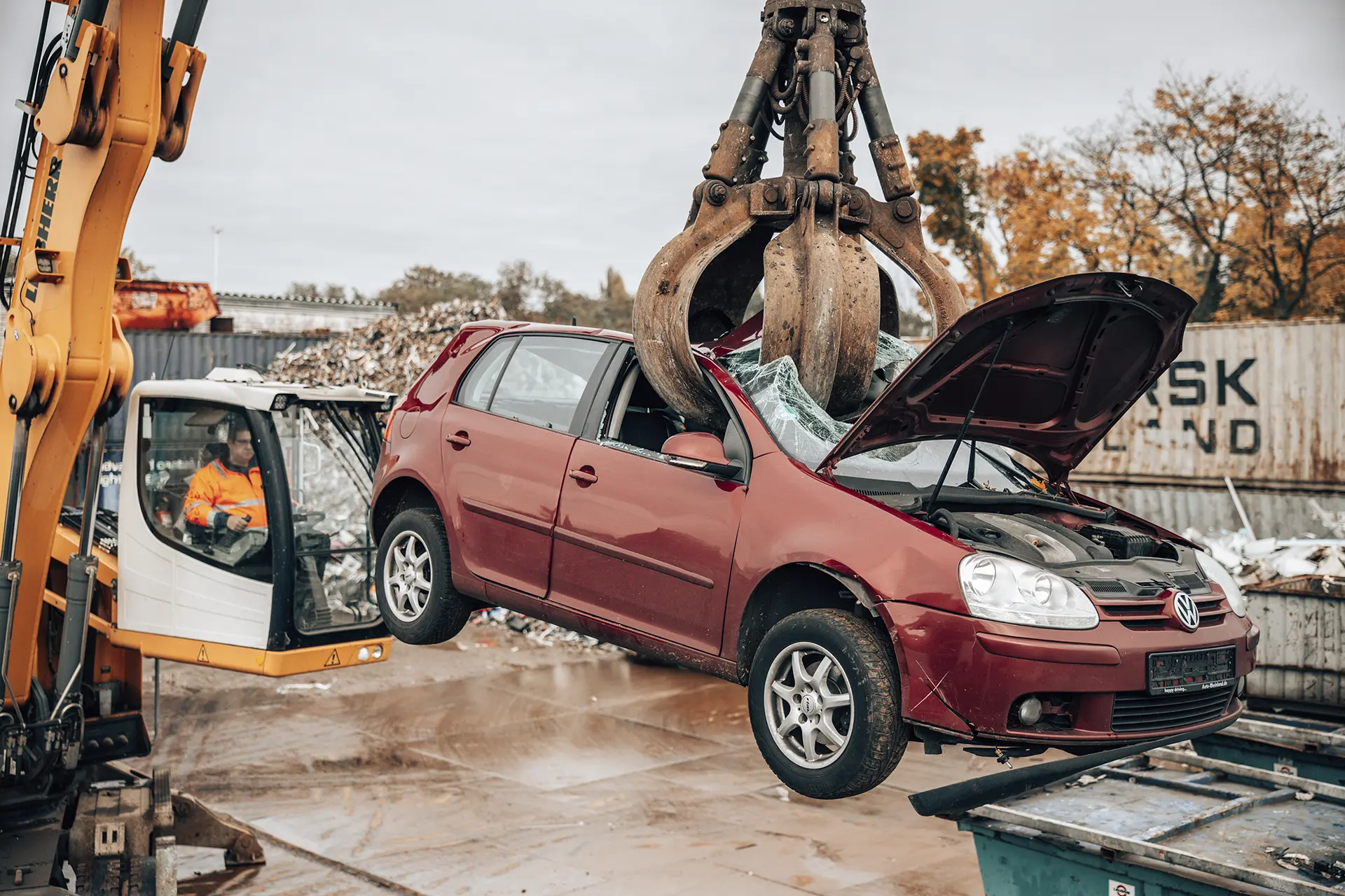 Schrotthandel Düsseldorf Ossenbühl Schrott Bagger beim Umsetzen von Altauto Nahaufnahme